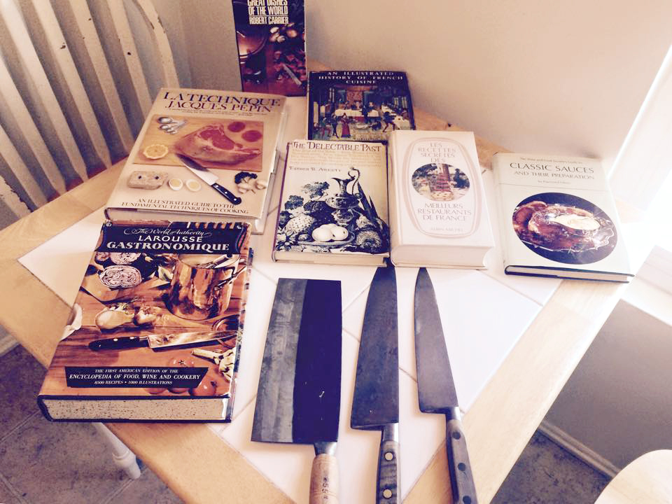 Private cooking classes LA. Several cookbooks and knives on display on a white table.
