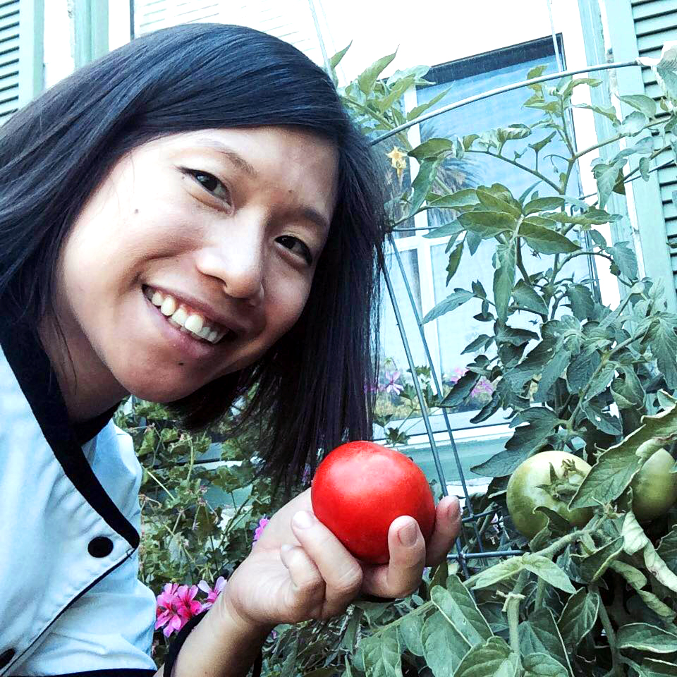 Personal Chef Los Angeles - Eliette holding a tomato in front of a tomato plant.