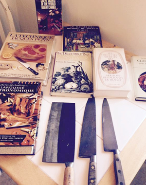 Vintage cookbooks and knives on table.