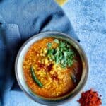 Bengali Moong Dal or Bhaja Moonger Daal in bowl, kashmiri chili powder on the lower right and grey and mustard-colred towels underneath.