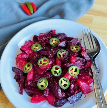 Ethiopian Beet Salad with jalapeno, on white plate with silverware.