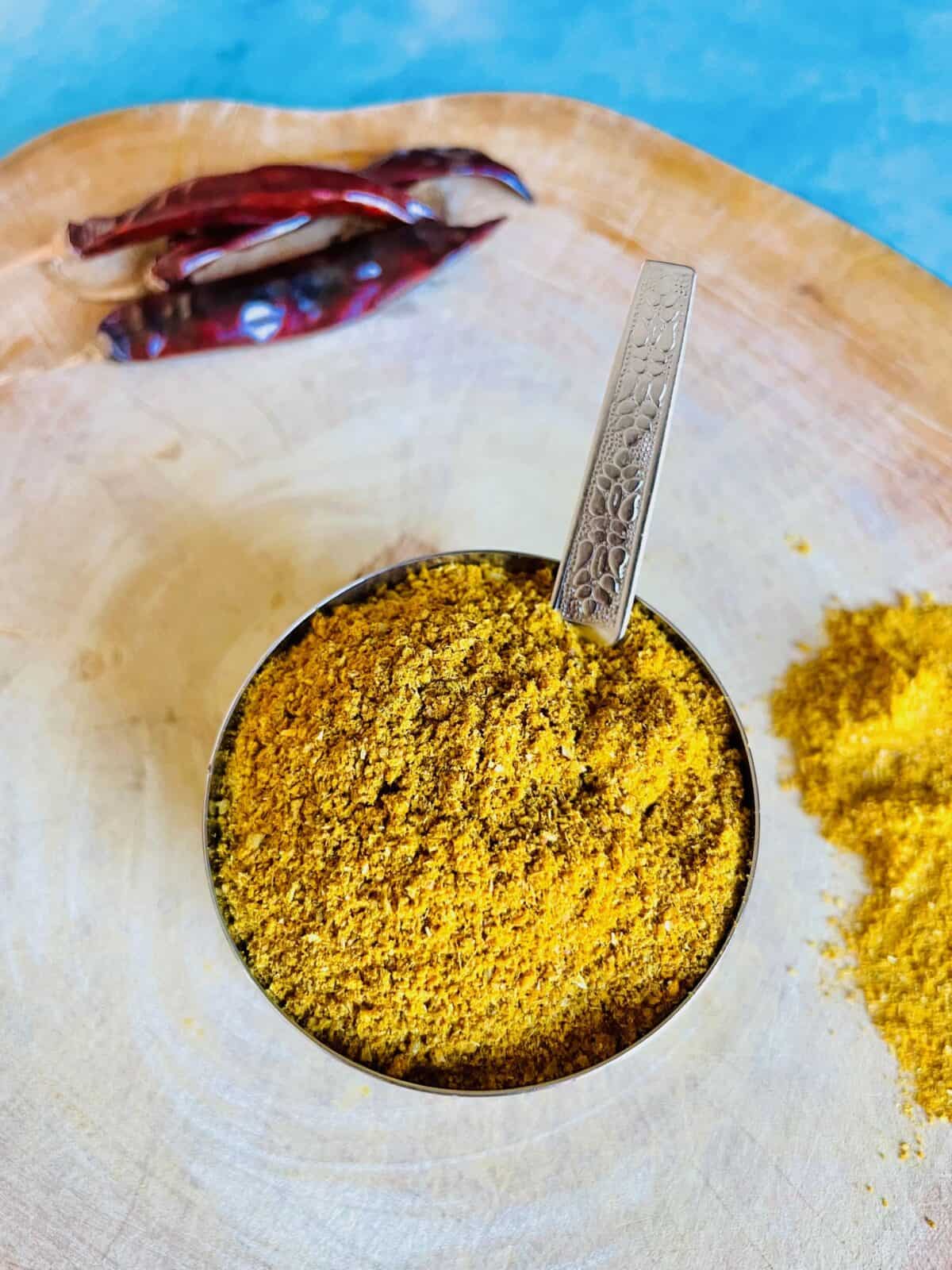 Mauritian curry powder in stainless steel bowl with a spoon.